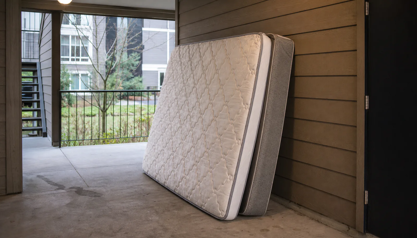 Mattress and box spring positioned neatly in a covered pickup area