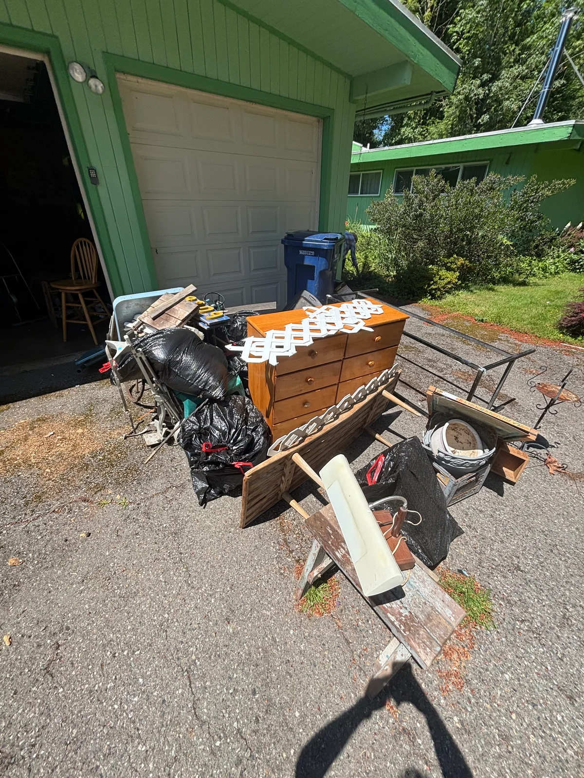 Furniture, bags, and household items staged beside a driveway