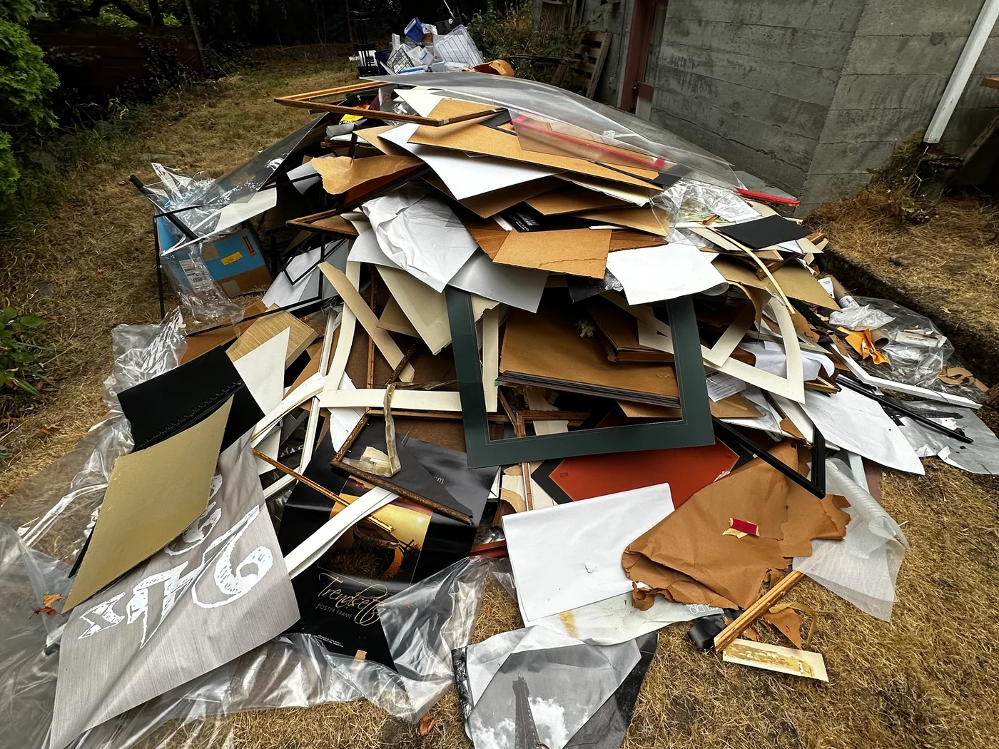 Large pile of frames and cardboard beside a brick building before pickup