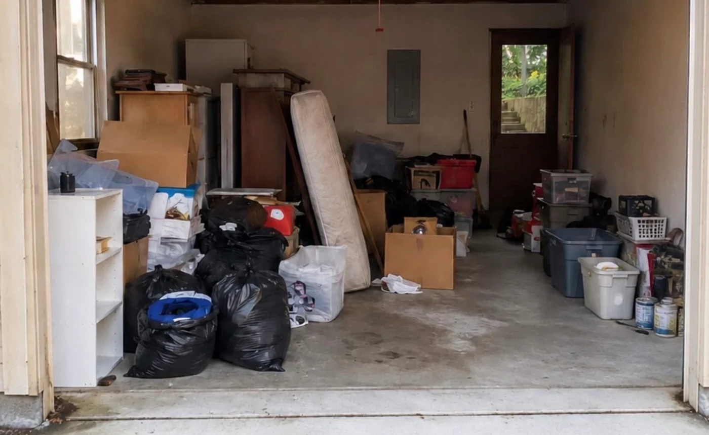 Garage containing furniture, bags, bins, and loose contents before removal