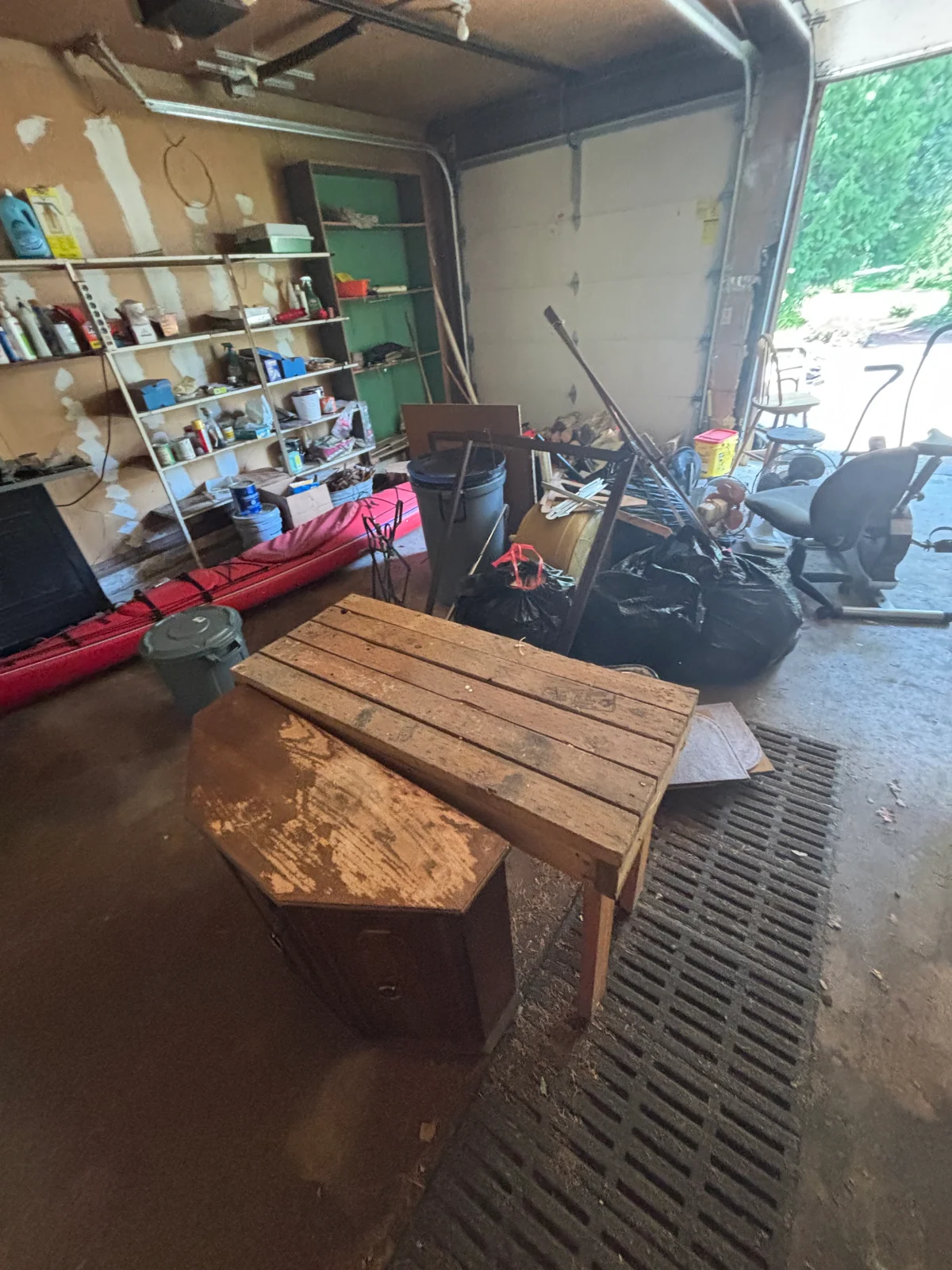 Garage with a kayak, shelving, furniture, bags, and loose contents before removal