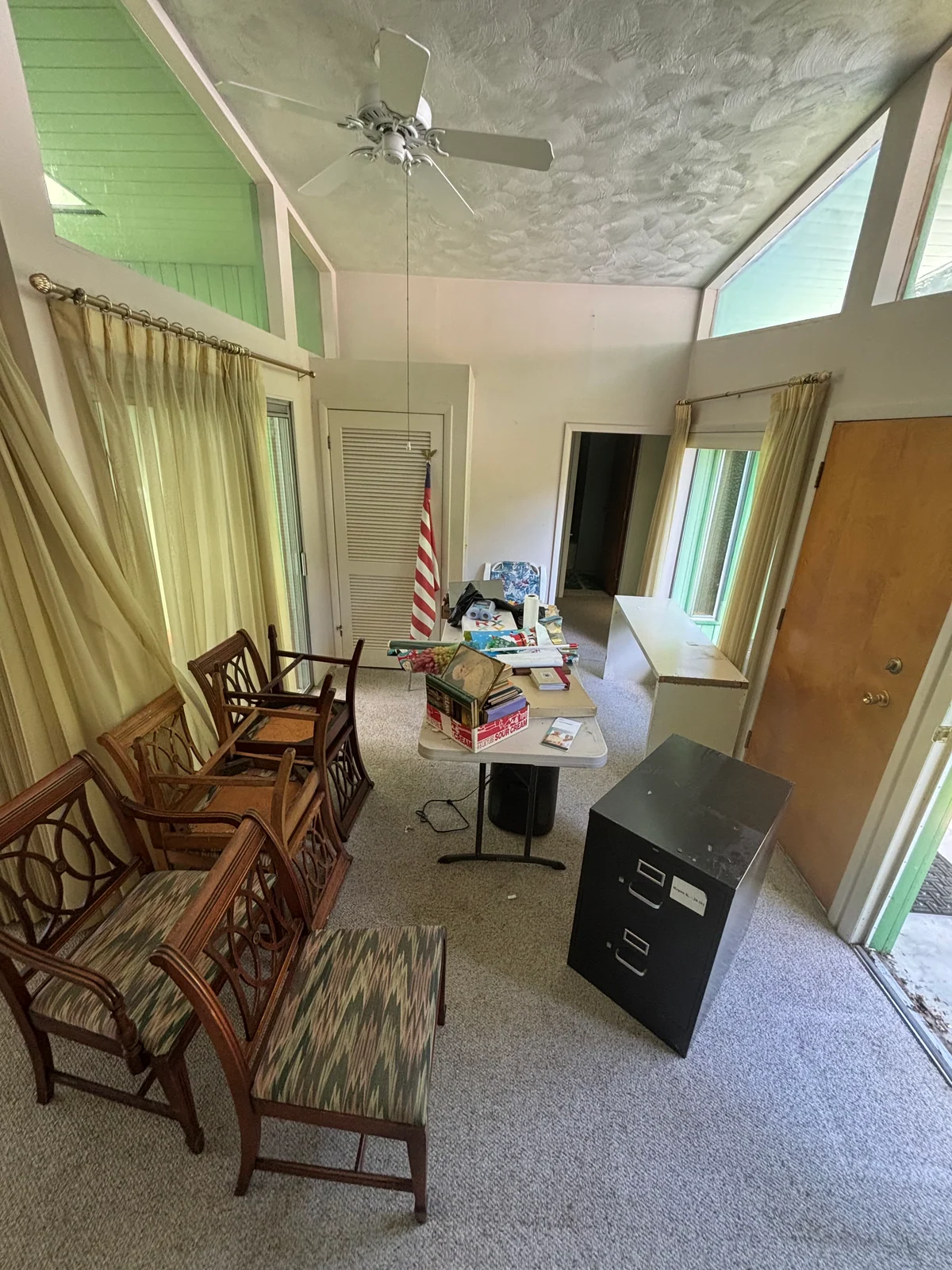 Living room with chairs, a filing cabinet, a table, and household contents before removal